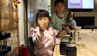 a child holds up a potted plant banner